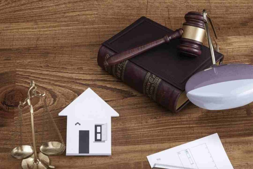 Model house, scales, and a gavel on a book.